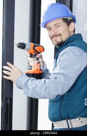 smiling worker fixing a window handle using a cordless screwdriver Stock Photo
