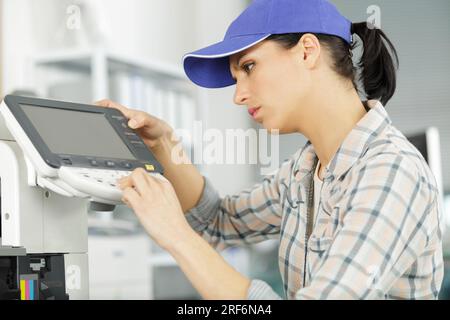 happy woman smiling at the camera fixing a printer Stock Photo