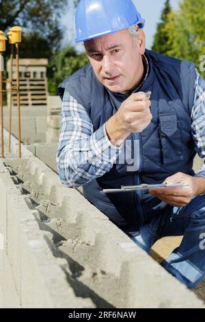 a builder checking concrete wall Stock Photo