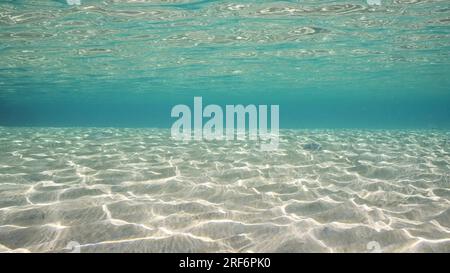 Sandy shallow water in sunburst and glare on seabed sand. Sunlight passes through surface of turquoise water and glares on sandy bottom in shallow wat Stock Photo