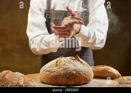 Baker cooking bread. Man slaps flour over the dough. Men's hands with flour clap. Stock Photo