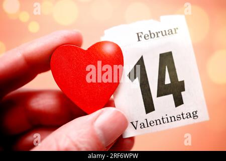 Hand hält rotes Herz und Kalenderblatt vom 14. Februar, Symbolfoto Valentinstag Stock Photo