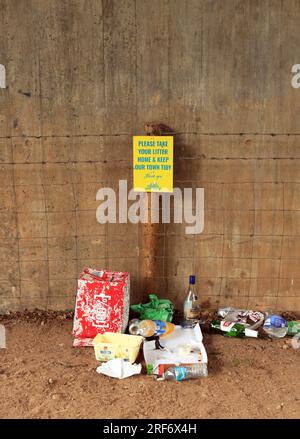 Take your litter home sign surrounded by litter. Stock Photo