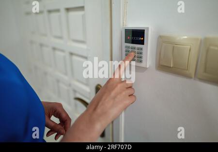 Woman putting code in alarm system panel at home. Stock Photo