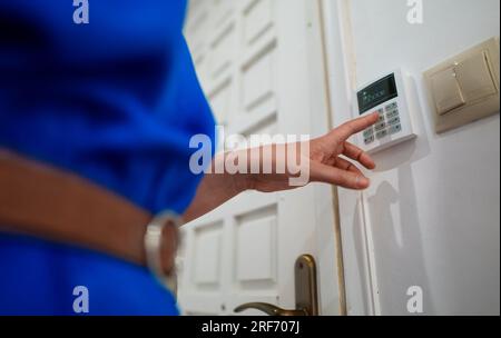 Woman putting code in alarm system panel at home. Stock Photo
