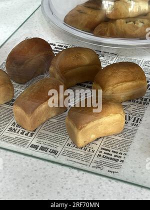 Home baked sandwich breads. Small breads with fluffy crumb and golden crust for delicious sandwiches. Fresh baked buns, bread bag on the table. Stock Photo