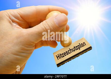 FOTOMONTAGE, Hand hält Stempel mit der Aufschrift Hitzeschutzplan Stock Photo