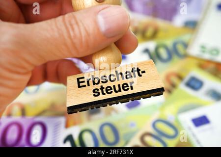 FOTOMONTAGE, Hand hält Stempel mit Aufschrift Erbschaftsteuer vor Euroscheinen Stock Photo