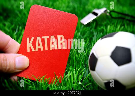 FOTOMONTAGE, Hand hält rote Karte mit Aufschrift Katar auf Fußballrasen, Symbolfoto Boykott der Fußball-Weltmeisterschaft Stock Photo