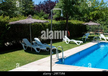 Details in a swimming pool, whether they are the chair with its umbrella, the stainless steel ladder or the jets of the treatment plant Stock Photo