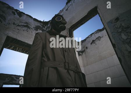 A man in gas mask walking inside an old building, low angle shot, good for book cover Stock Photo