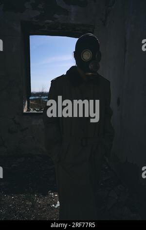 A man in gas mask walking inside an old building, hands in pockets, vertical shot, good for book cover Stock Photo