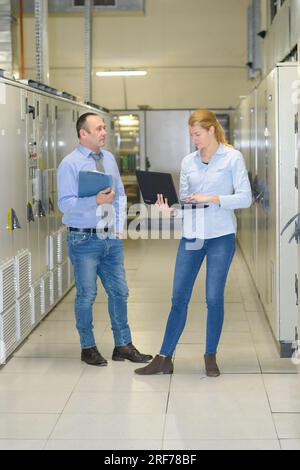 technicians working on laptop in server room Stock Photo