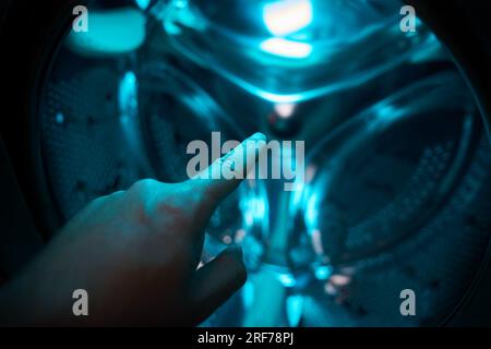 A Hand inside washer pointing a finger in a blue light, future, sci-fi, concept Stock Photo