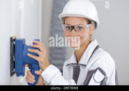 female construction worker smoothing wall surface Stock Photo