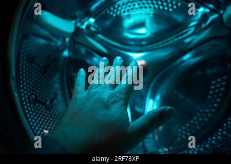A Hand inside washer in a blue light, future, sci-fi, concept Stock Photo
