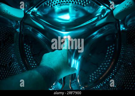A Hand inside washer pointing a finger in a blue light, future, sci-fi, concept Stock Photo