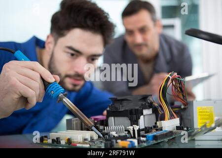 male electronics worker using soldering iron Stock Photo