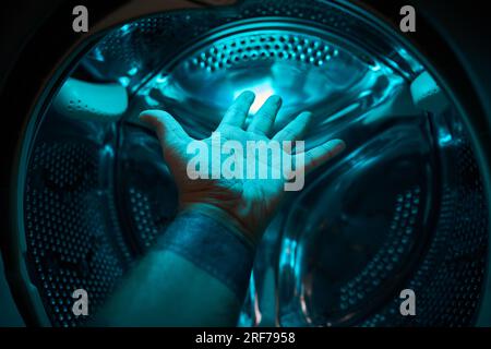 A Hand inside washer in a blue light, future, sci-fi, concept Stock Photo