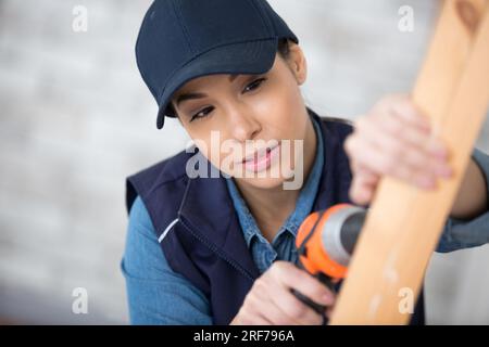beautiful young woman using cordless screwdriver on wood Stock Photo