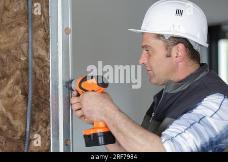 man fixing metal frame using electrical screwdriver Stock Photo