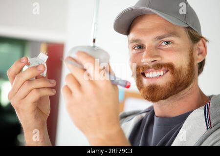 male electrician installing bulb in a suspended light fitting Stock Photo