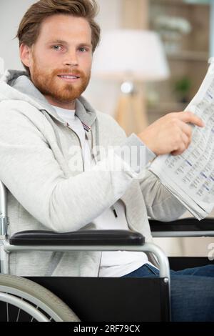 a man in wheelchair reading newspaper Stock Photo