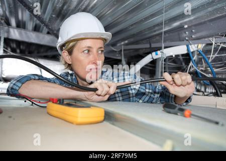 female electrician working on false ceiling Stock Photo