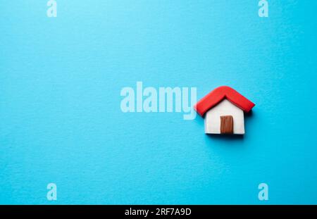 Miniature house on a blue background. Buying and selling housing. Construction industry. Design and architectural services. Property insurance. Real e Stock Photo