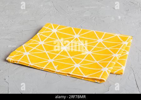 top view with yellow empty kitchen napkin isolated on table background. Folded cloth for mockup with copy space, Flat lay. Minimal style. Stock Photo
