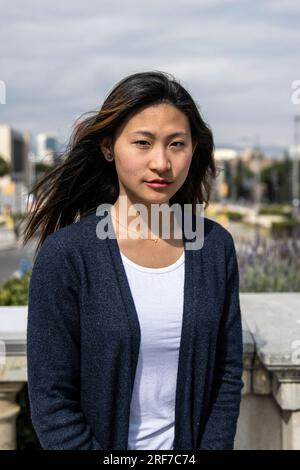 Young beautiful confident woman looking at camera standing outdoors. Determined lady staring at camera in a casual style in the street. Stock Photo
