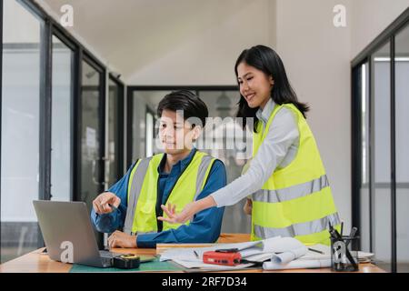 Two young man and woman engineers meeting, working, discussing, planing, designing, measuring layout of building blueprints in construction site floor Stock Photo