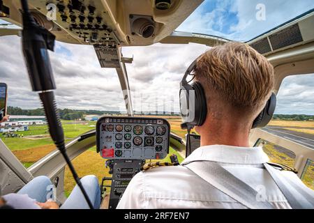 View through the front cockpit of a helicopter with details of instruments and the pilot and landscape to the distance. Stock Photo