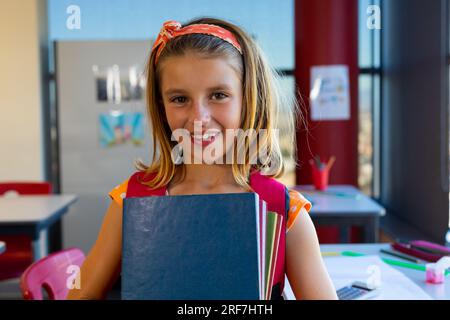 Portrait of a schoolgirl with books in a classroom Stock Photo - Alamy