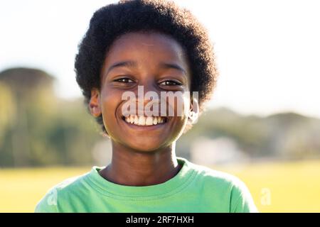 Portrait of african american schoolboy smiling in sunny elementary school sports field Stock Photo