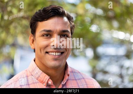 Portrait of biracial male teacher smiling in the garden at elementary school Stock Photo