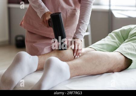 Close-up of therapist massaging legs of patient with special medical equipment Stock Photo