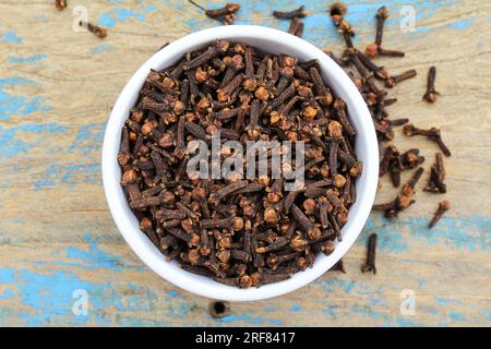 Dried Cloves spice in a bowl on old wooden background top view Stock Photo