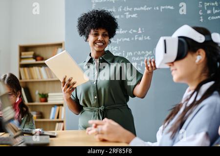 Smiling African American teacher having IT lesson with students while they using VR glasses Stock Photo