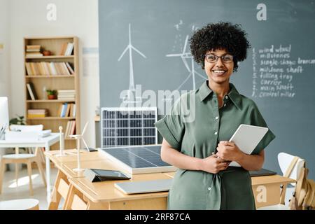 Portrait of African American teacher with tablet pc smiling at camera while standing in the classroom Stock Photo