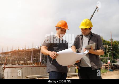 Team of construction workers discussing project details with blueprint in construction site. Stock Photo