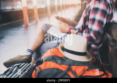 Traveler sitting and using smartphone at train station. Travel concept with vintage tone. Stock Photo