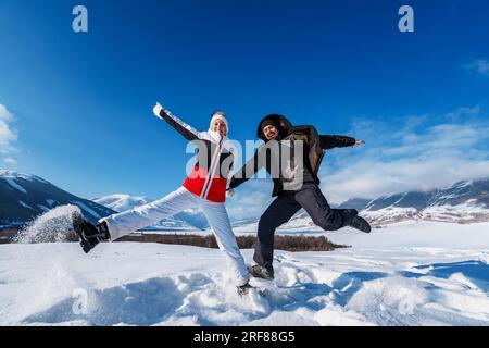 Young happy man and woman jumping on mountains background in winter season Stock Photo