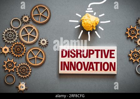 Disruptive innovation text on wooden block. Between gears, precision mechanisms and drawn light bulb, business concept Stock Photo