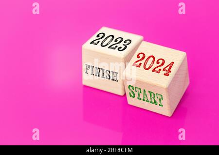 finish 2023 and start 2024, Wooden blocks with text on a beautiful fuchsia background, Coming new year, New business plans, copy space Stock Photo