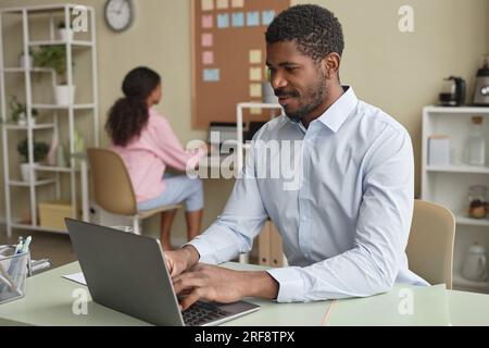 Portrait of adult African American business expert working with laptop at desk in office, copy space Stock Photo