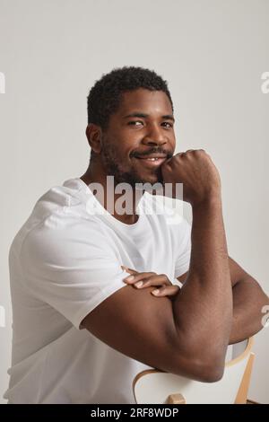Minimal portrait of handsome black man smiling at camera confidently against white background Stock Photo