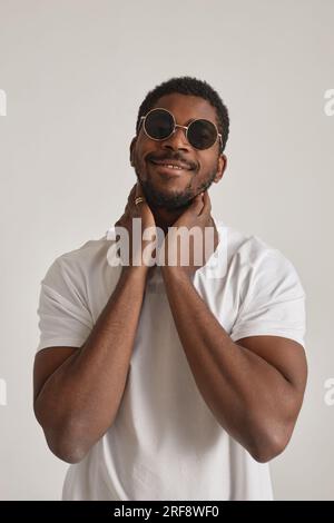 Minimal portrait of African American man with sunglasses posing in studio against white Stock Photo