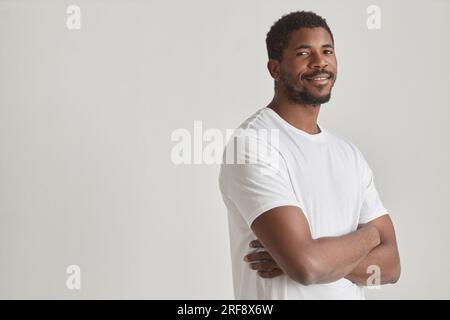 Minimal portrait of handsome black man posing in studio against white background standing with arms crossed, copy space Stock Photo