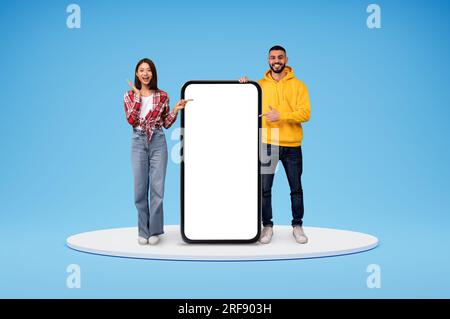 Excited arab man and asian woman standing by big phone Stock Photo